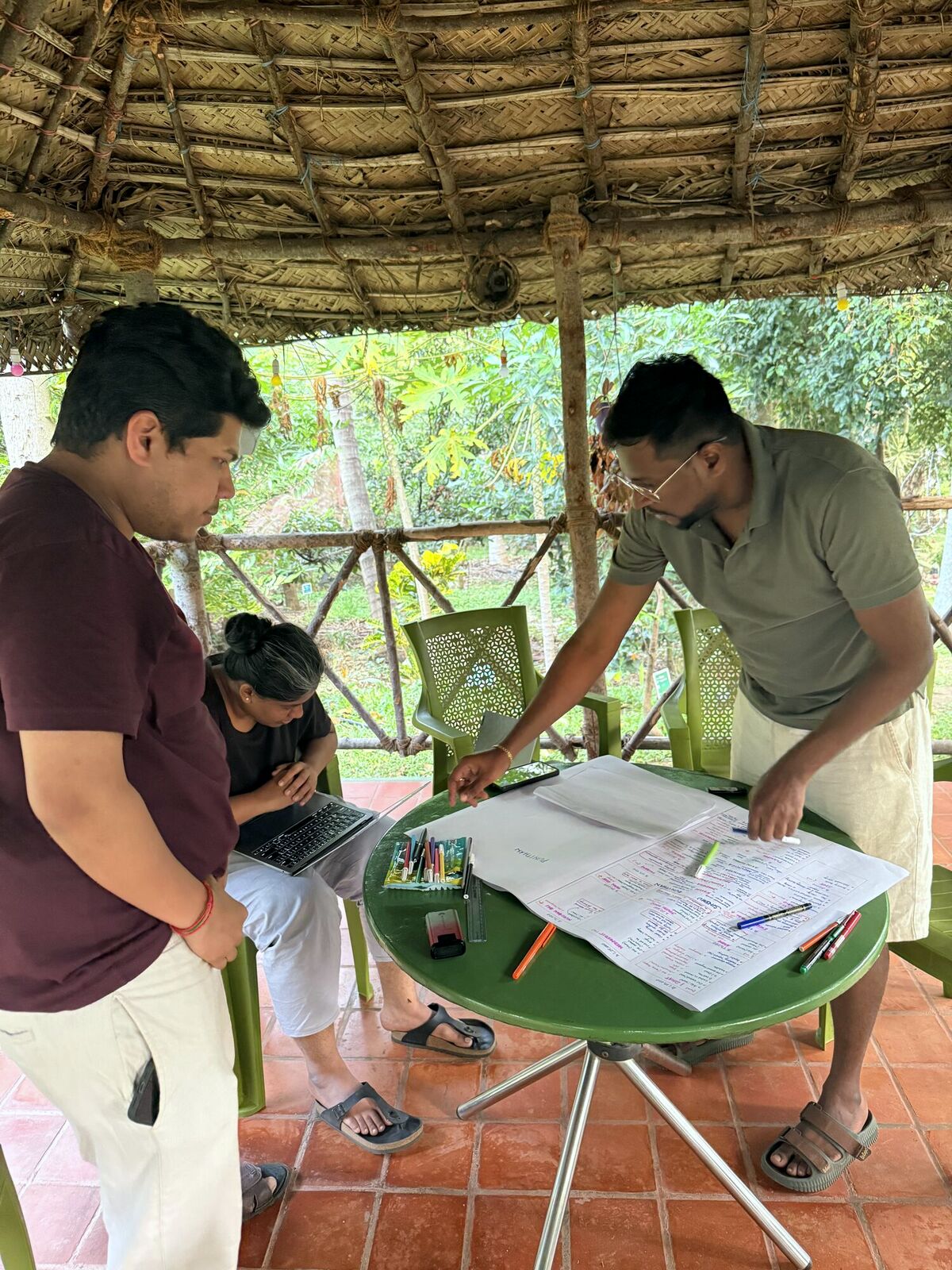 The tribe working through a problem in a forest hut