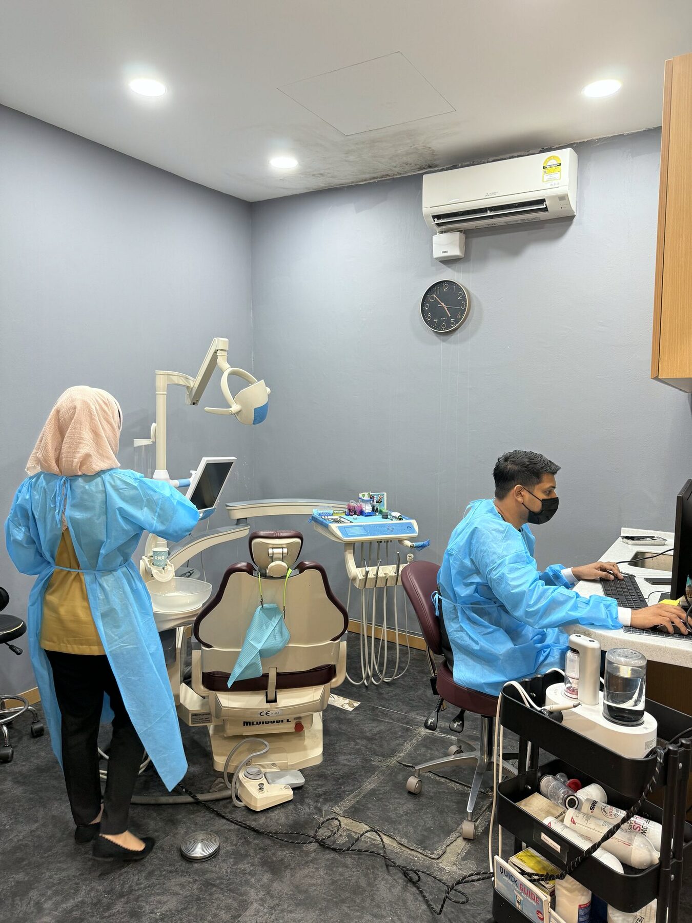 A modern dental operatory with a dentist and assistant treating a patient